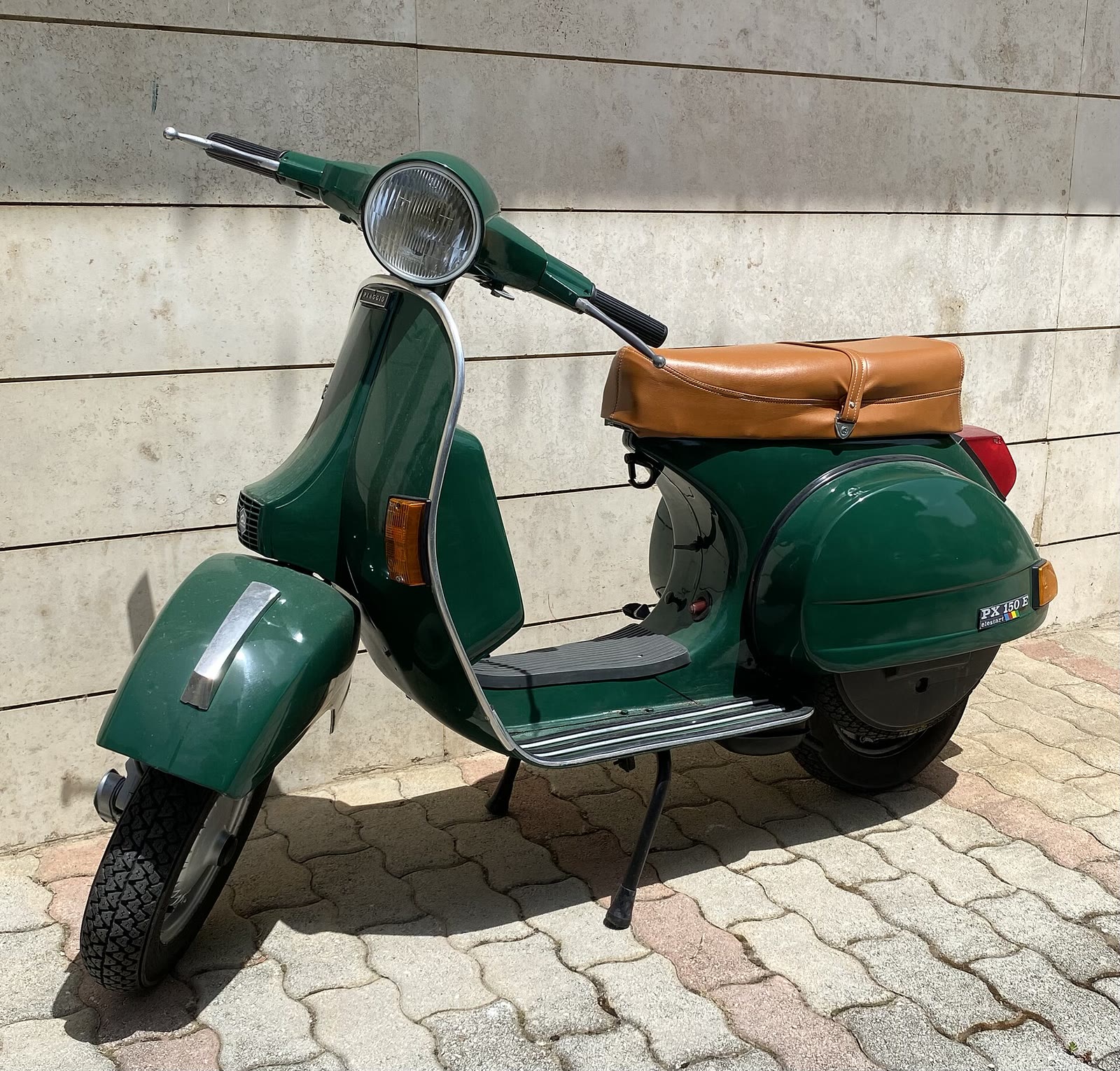 Vespa PX 150 verde parcheggiata contro un muro