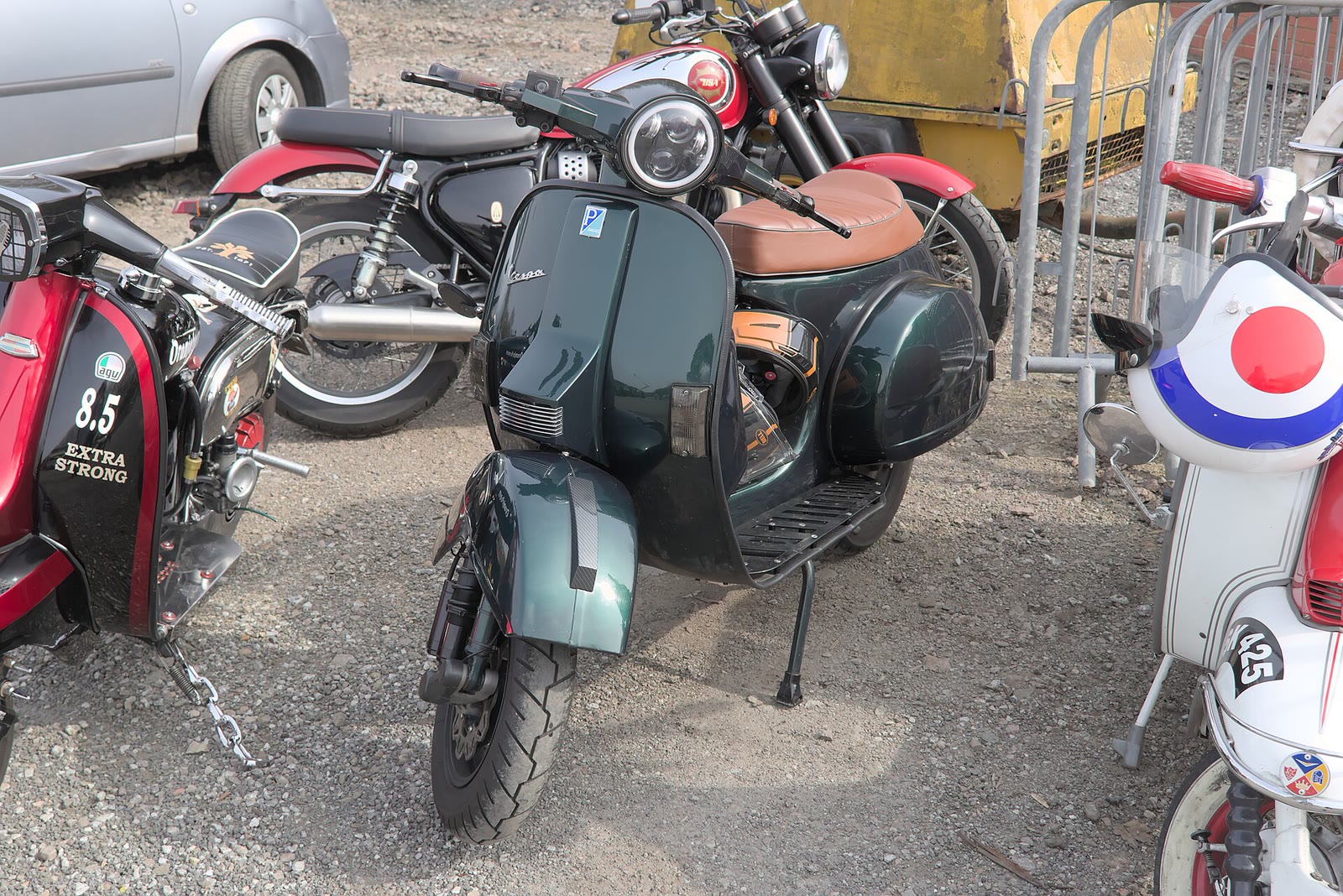 Vespa PX 200 E blu tra altre moto in un parcheggio