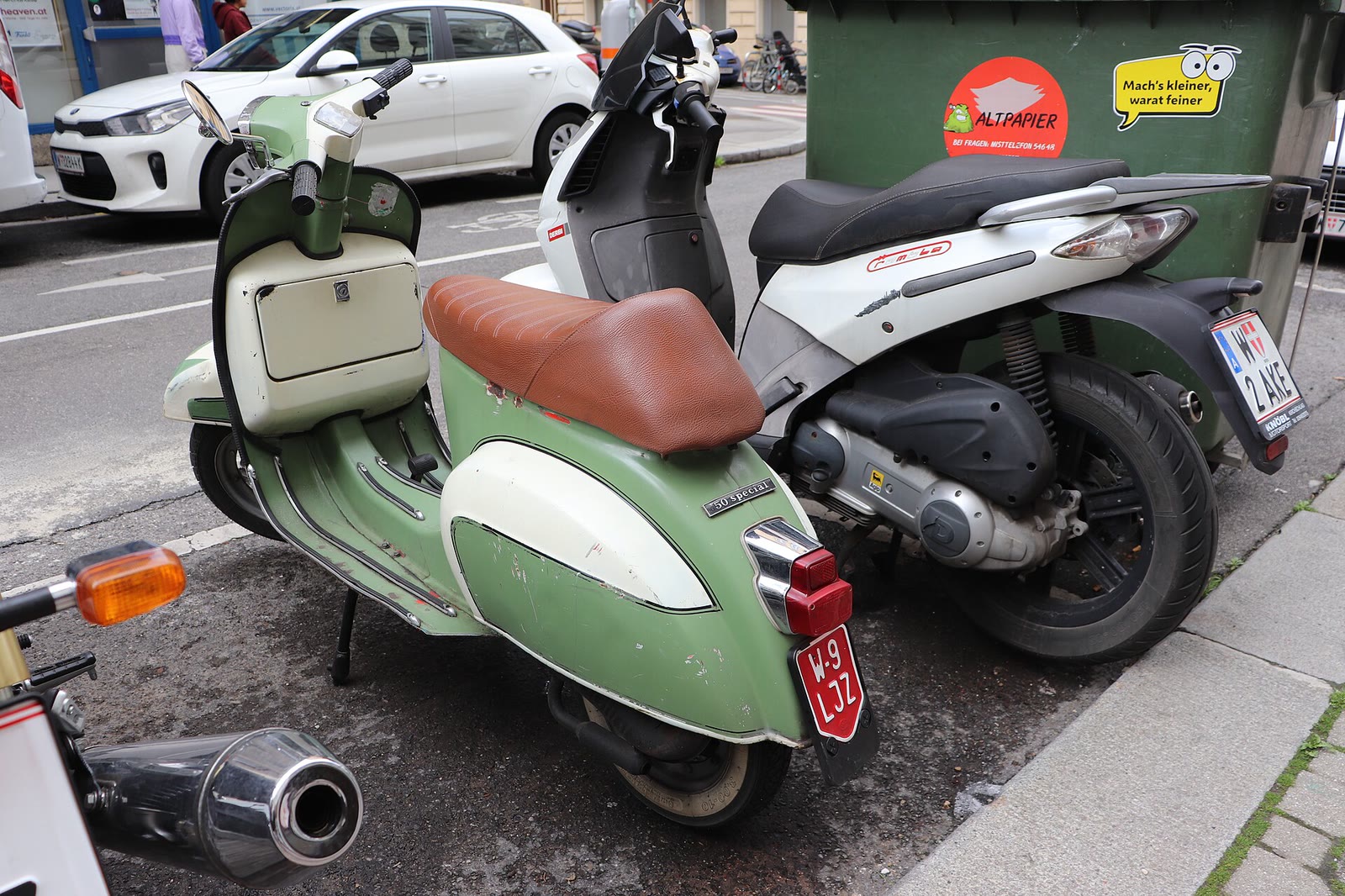 Vespa 50 Special verde e bianca parcheggiata in una via di città