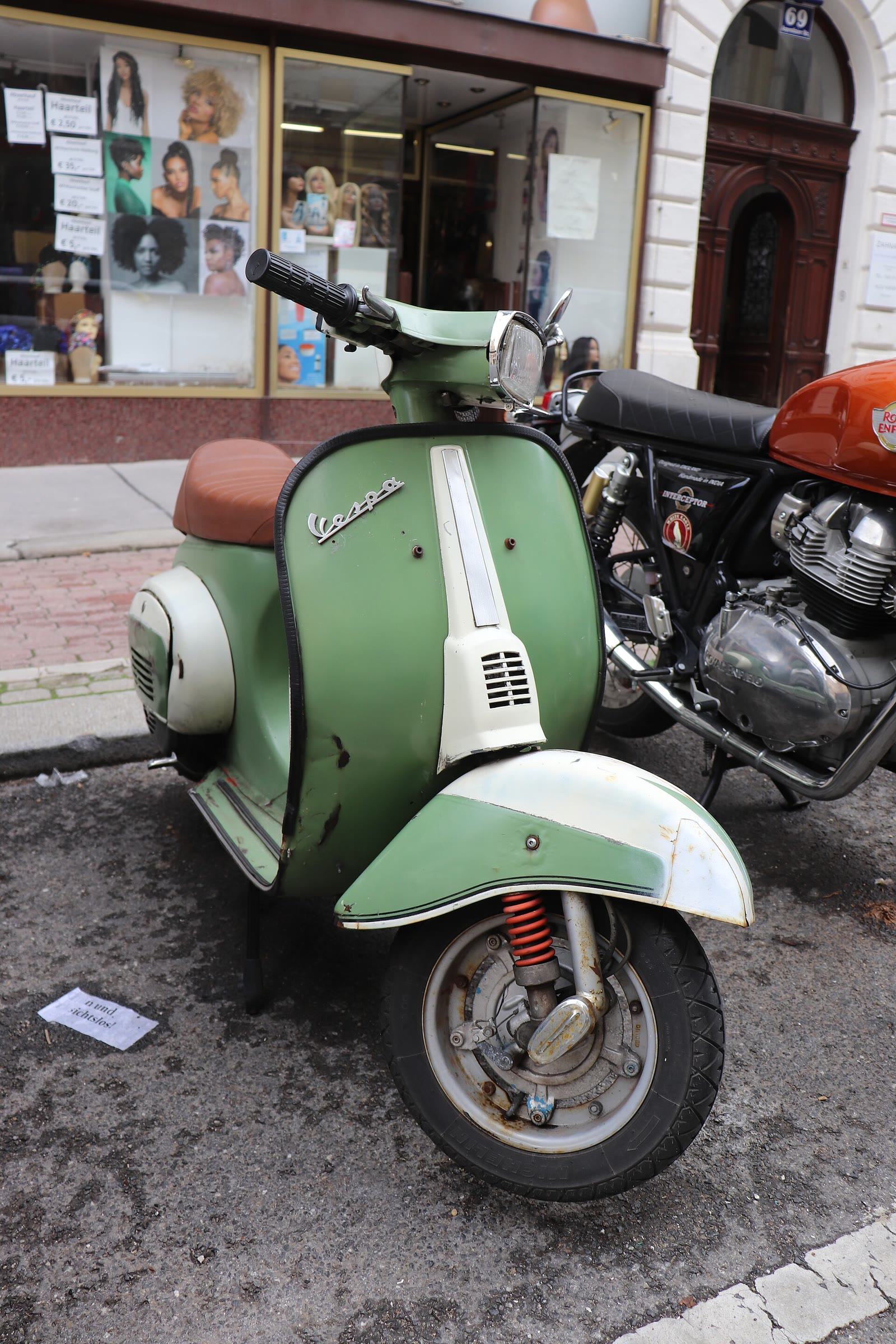 Vespa 50 Special verde e bianca parcheggiata in una via di città (2/2)